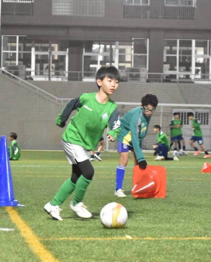 サッカーボールを蹴っている少年